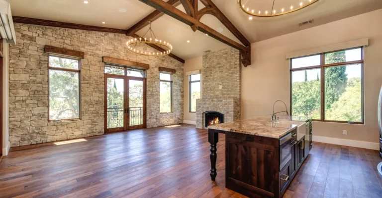 Interior of open concept great room, in a high-end above garage home addition, featuring wood floors, exposed beams and stone accents.